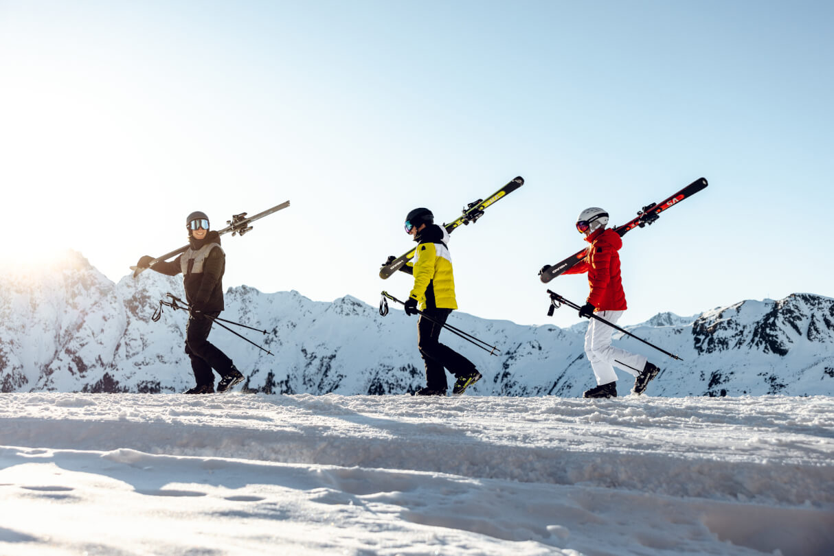 Grupa narciarzy maszeruje ze sprzętem na ramieniu